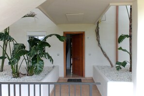 A staircase with a wooden door at the top, surrounded by white walls and plants. - Garden Apartment. Golf by the Sea in Estepona (Estepona)
