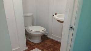 A small bathroom with a toilet, sink, and wooden flooring. - Cozy 1BR Fort Myers Getaway – Minutes to Downtown! (Fort Myers)