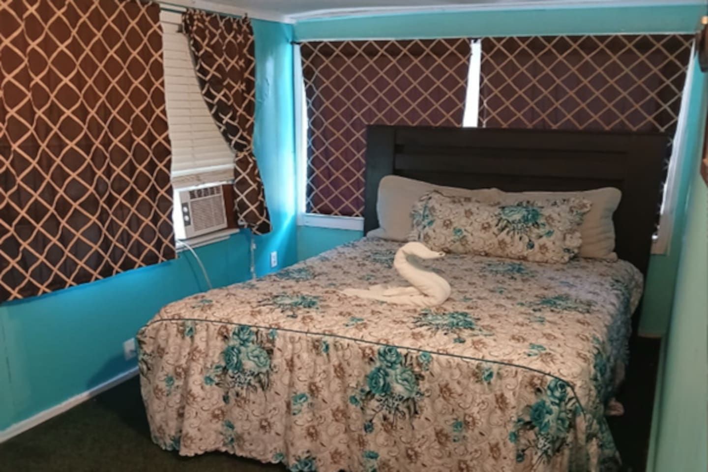 A bedroom with a bed, a window with blinds, and a wall with a patterned design.