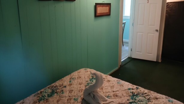 A room with teal walls, a bed with floral bedding, a framed picture, and a door labeled '3'. - Cozy 1BR Fort Myers Getaway – Minutes to Downtown! (Fort Myers)