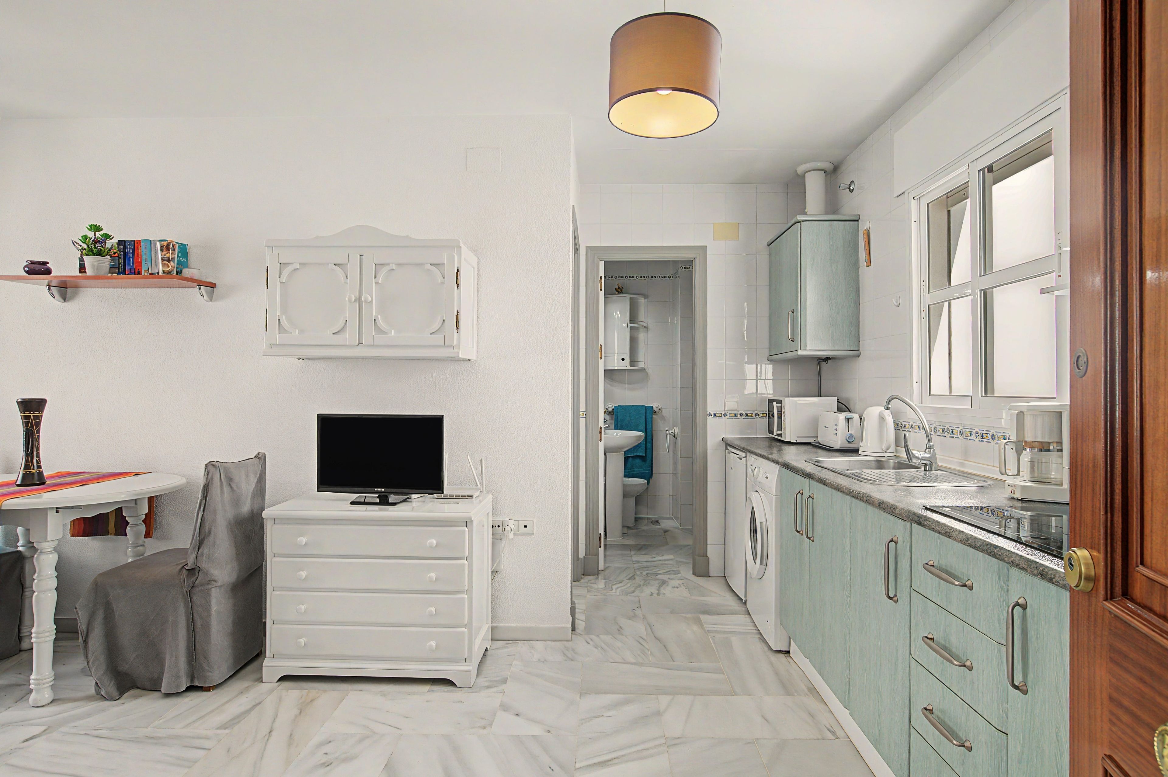 A compact kitchen with a sink, microwave, and cabinets.