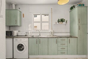 A compact kitchen with a washing machine, microwave, toaster, and a coffee maker. - Apartment 'Annett - Families Only' with Wi-Fi (Conil de la Frontera)