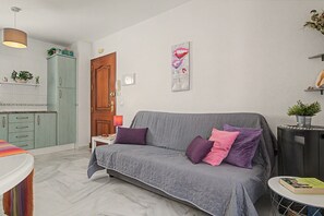 A living room with a grey sofa, a small round table, a bookshelf, and a door. - Apartment 'Annett - Families Only' with Wi-Fi (Conil de la Frontera)