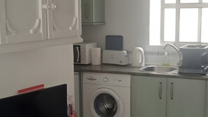 Ett modernt kök med tvättmaskin, mikrovågsugn och diskho.