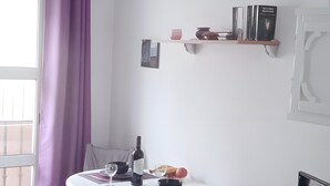 Ett rum med ett matbord, stolar, en tv och ett fönster med gardiner.