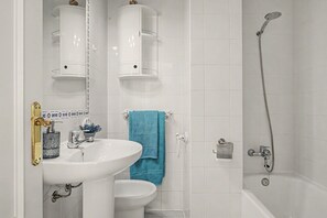 Un baño con lavamanos blanco, inodoro, ducha y toallero.