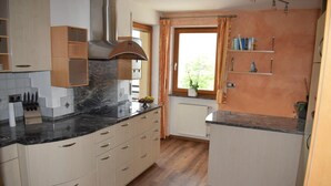 A kitchen with wooden cabinets, a marble countertop, and a window with curtains. - Apartment 'Residence Ladurn Erde' with Mountain View, Private Terrace and Wi-Fi (Tirol)