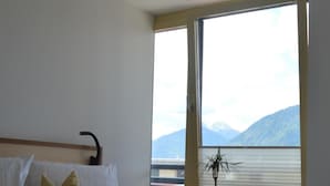 A bedroom with a large bed, a bedside table, a potted plant, and a window with a mountain view. - Apartment 'Residence Ladurn Erde' with Mountain View, Private Terrace and Wi-Fi (Tirol)