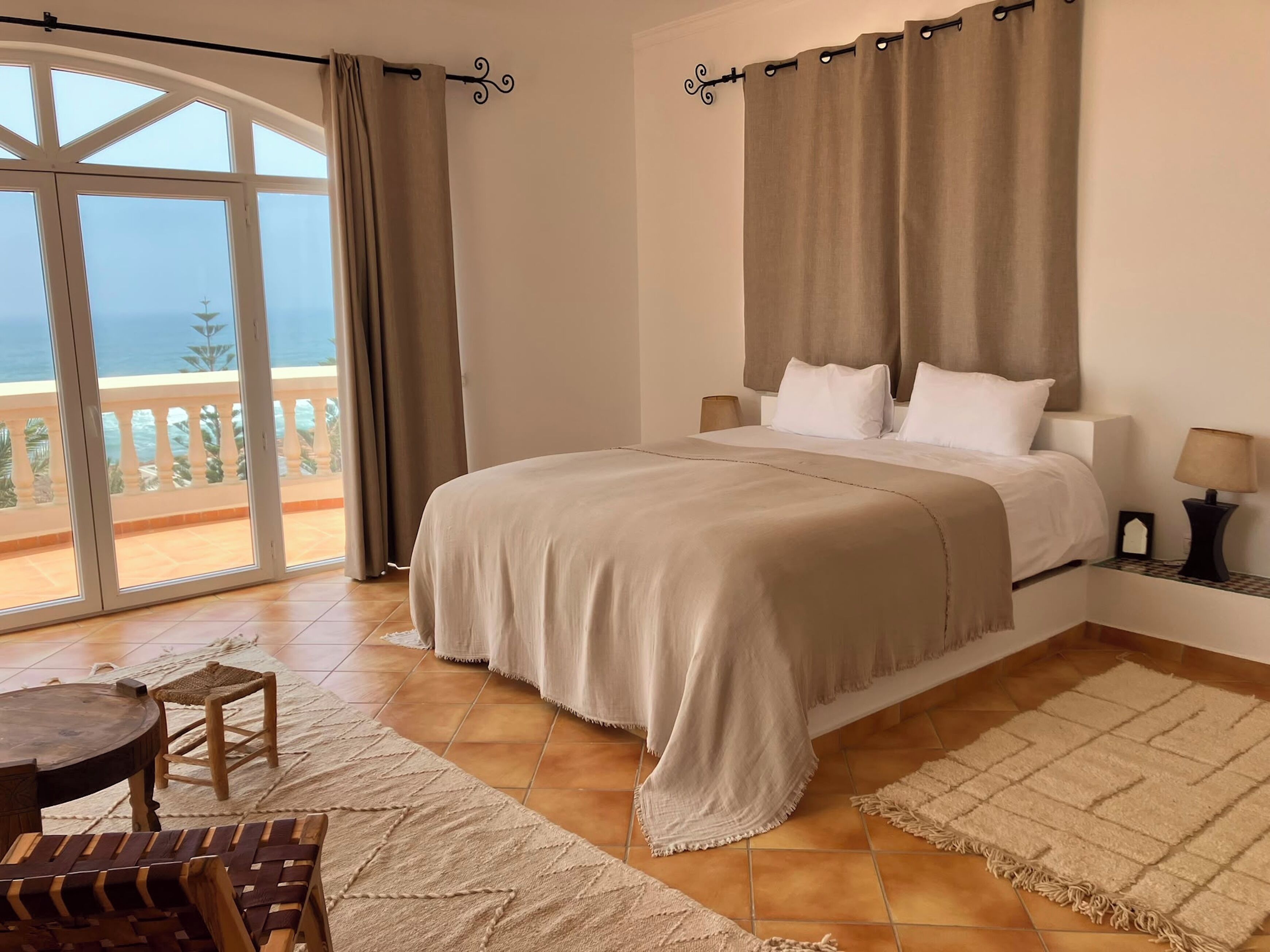 Ein Schlafzimmer mit großem Bett, einem Balkon mit Aussicht und einem Essbereich mit Tisch und Stühlen.