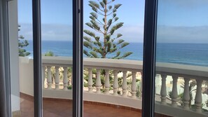 Un balcon avec vue sur l’océan et un pin.