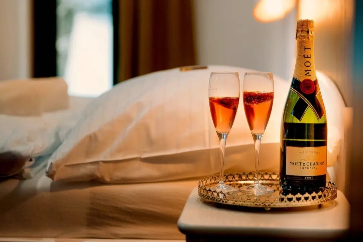 A bed with a bottle of Moët & Chandon Imperial Brut champagne and two glasses on a tray.