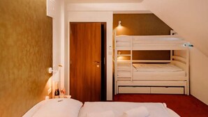 Une chambre d’hôtel avec un lit superposé, une porte en bois et une moquette rouge.