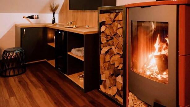 Une cuisine moderne avec un poêle à bois, un meuble en bois et un petit tabouret.