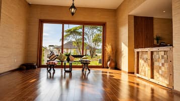A spacious room with a large sliding glass door leading to a garden, a wooden floor, and a modern light fixture.