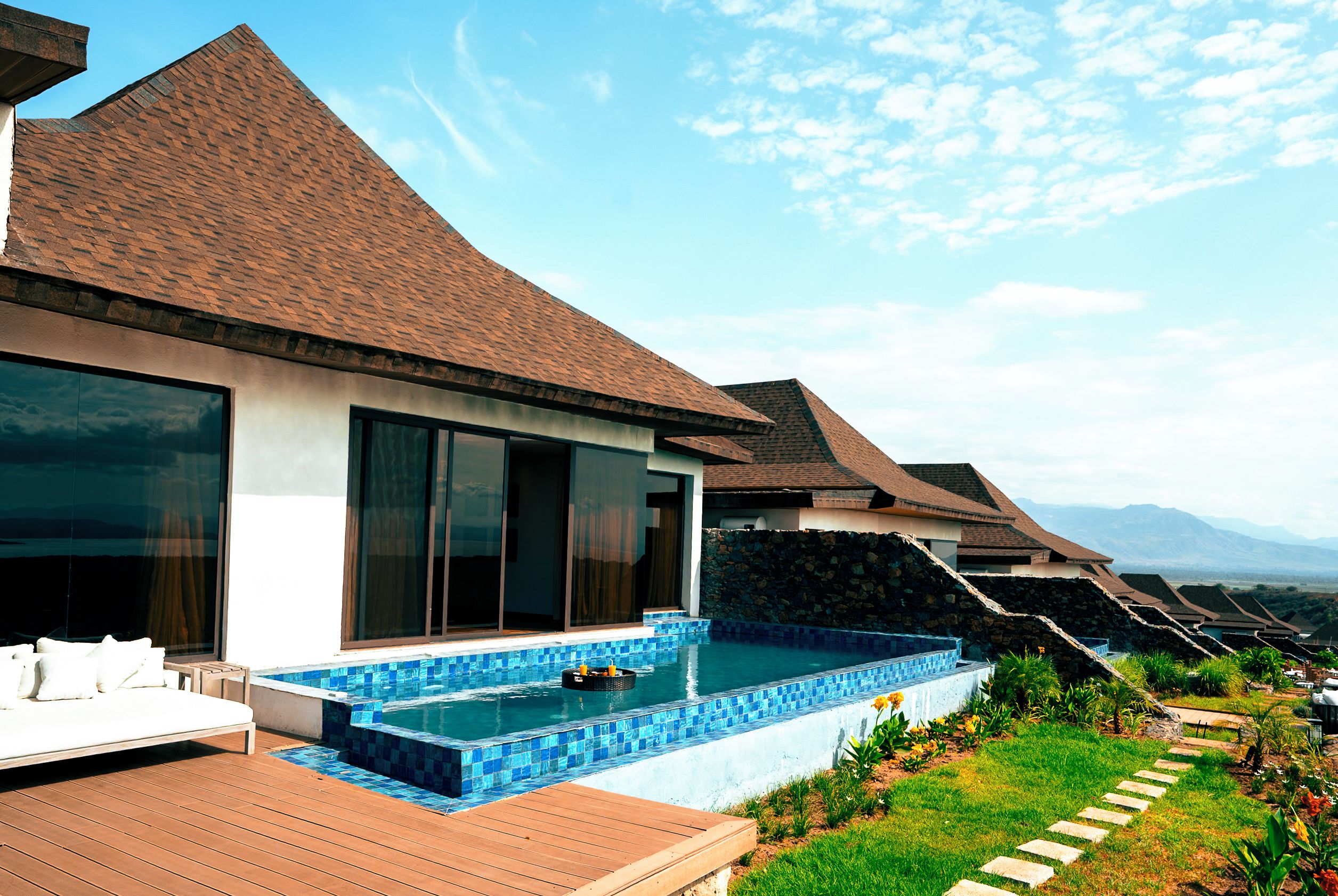 Un resort moderno con piscina, ventanas amplias y vistas a la montaña.
