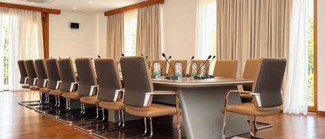 A conference room with a long table, multiple chairs, microphones, and water bottles.