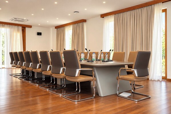 A conference room with a long table, multiple chairs, microphones, and water bottles.
