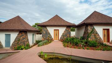 A row of three bungalow-style buildings with pitched roofs, a central pathway, and a small water feature.