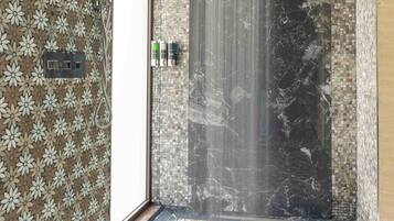A bathroom with a shower, patterned walls, and a tiled floor.