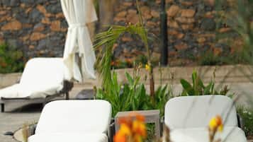 Un área junto a la piscina con sillones de descanso y sombrillas.