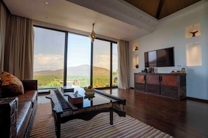 A spacious living room with a large window, a flat-screen TV, and a wooden coffee table. - Kuriftu Resort & Spa Arba Minch  (Arba Minch)