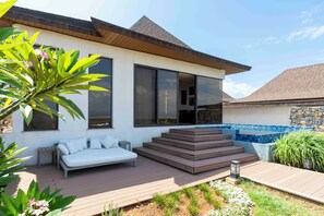 Una casa moderna con un patio, un sofá blanco y una piscina pequeña.