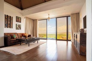 Un amplio salón con un gran ventanal corredera que da a una vista panorámica al exterior.