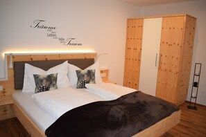 A bedroom with a bed, pillows, a wardrobe, and a wall with text.