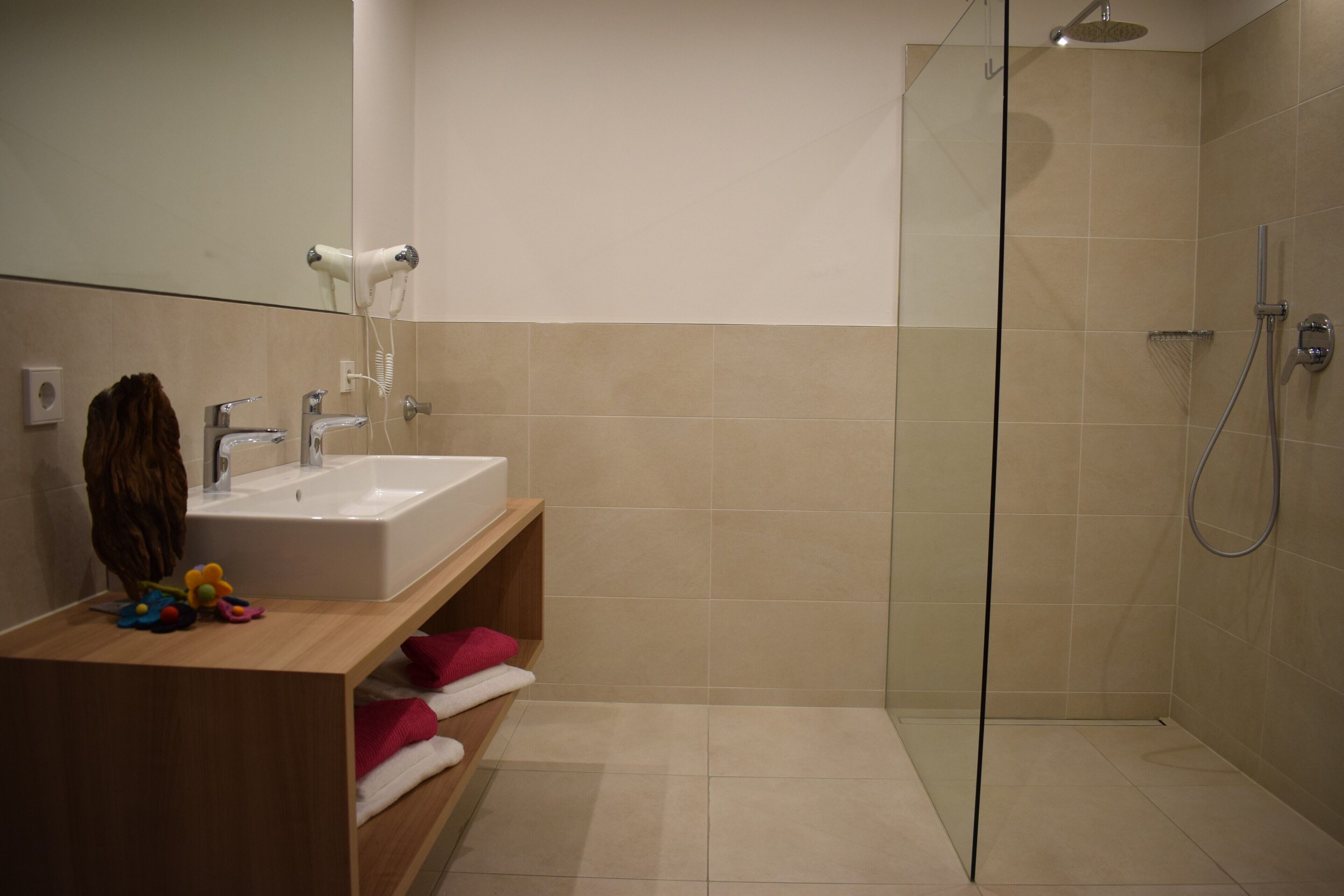 Ein modernes Badezimmer mit einer Duschkabine, einem Waschbecken und einem an der Wand montierten Föhn.