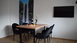 A dining area with a wooden table, black chairs, a fruit plate, a bottle of wine, and a small potted plant. - Apartment 'Residence Ladurn Herz' with Mountain View, Balcony and Wi-Fi (Tirol)