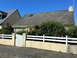 Ein Wohnhaus mit geneigtem Dach, einem verschlossenen Eingang und einem weißen Zaun.