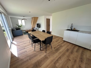 Eine moderne Küche mit einem Holzespeisetisch, schwarzen Stühlen, einem eingebauten weißen Schrank und einer Holztreppe.