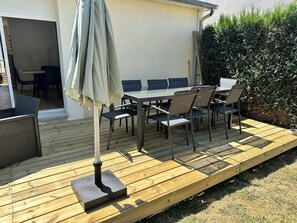 Eine Terrasse im Freien mit Tisch und Stühlen, einem Sonnenschirm und einem Holzdeck.