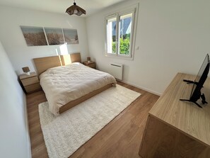 Ein Schlafzimmer mit Bett, Nachttischen, Schreibtisch und Fenster.