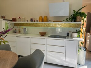 A modern kitchen with white cabinets, a black countertop, and a backsplash.