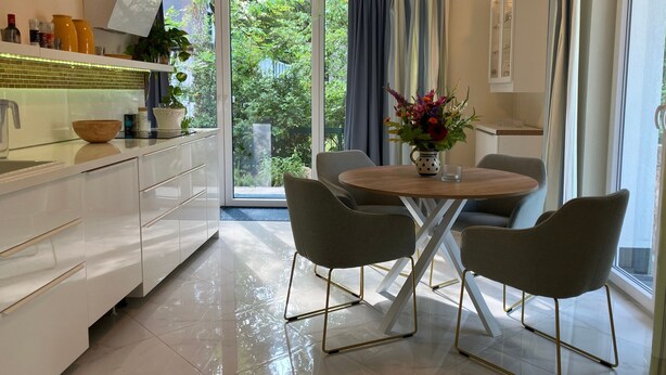 A modern kitchen with white cabinets, a wooden bowl, and a potted plant.