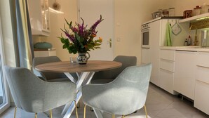 A modern kitchen with a round table, grey upholstered chairs, and a vase of flowers.