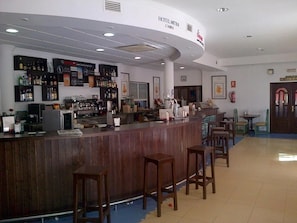 A hotel bar with a curved counter, bar stools, and a variety of bottles and glasses.