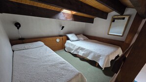 Quarto com duas camas, teto de madeira, espelho fixado na parede e uma pequena mesa.