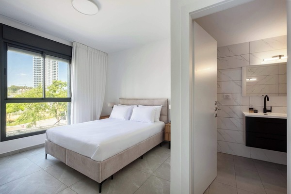Restful bedroom featuring a split Jewish bed, crisp white linens, modern ensuite access, and soft filtered daylight.