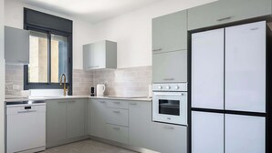 Une cuisine moderne avec des meubles gris, un lave-vaisselle, un four et un réfrigérateur à deux portes.