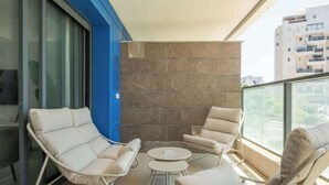 Un balcon avec deux fauteuils, une petite table ronde et un mur en pierre.