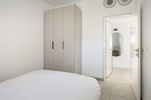 Une chambre à coucher comprenant un lit, une armoire et une porte donnant sur une salle de bain.