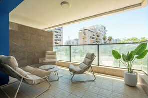 Un balcon avec deux fauteuils rembourrés, une petite table et une plante en pot.