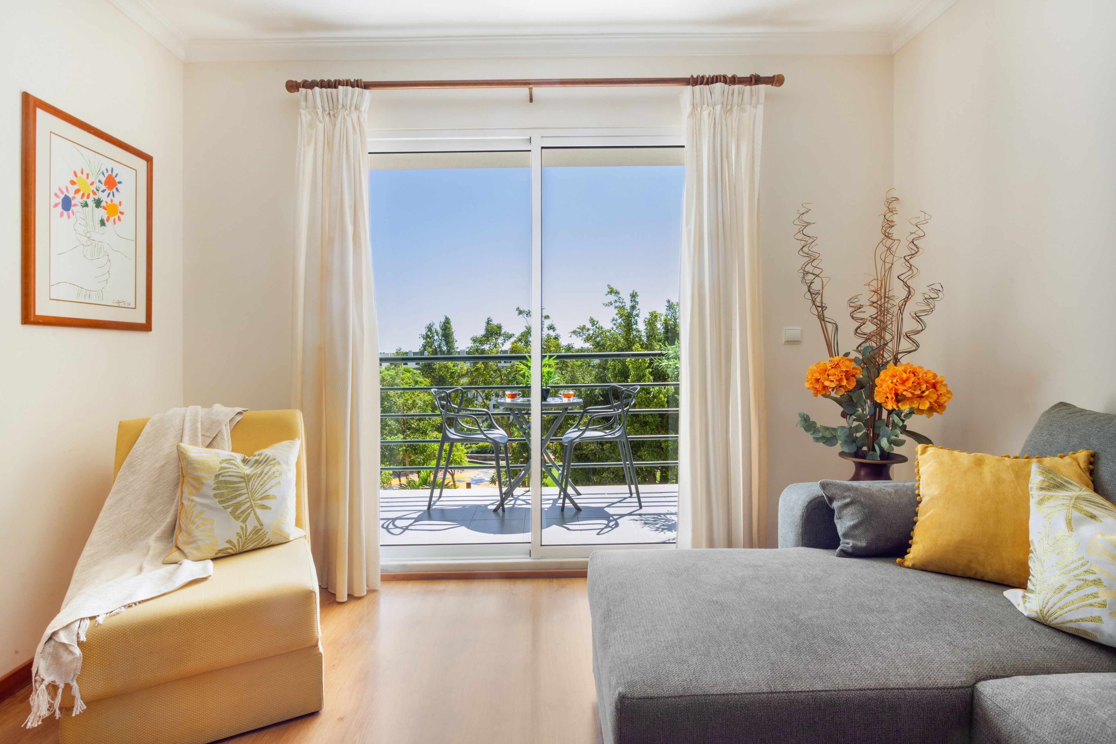 Ein Wohnzimmer mit einer Couch, einem Sessel und einem Balkon mit Gartenmöbeln.