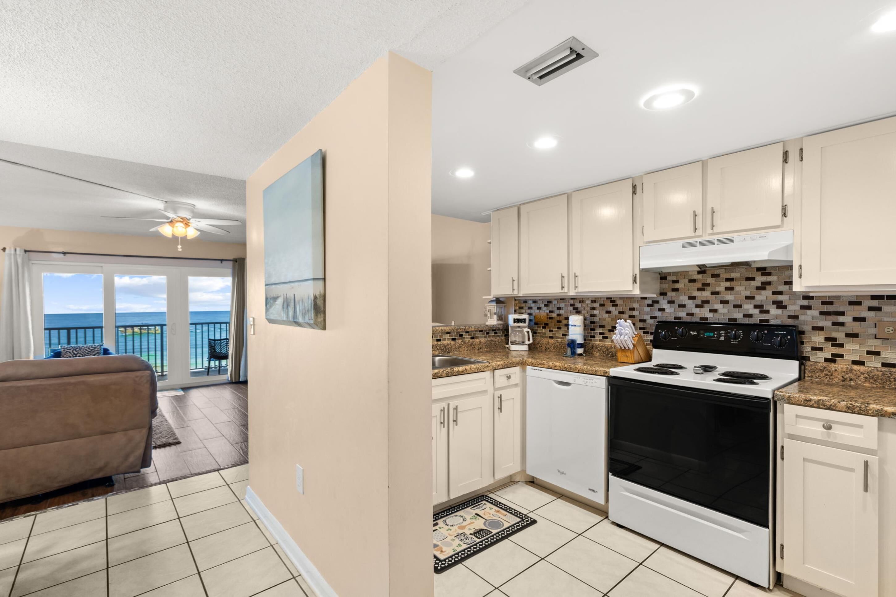 A modern kitchen with a large stove, white cabinets, and a view to the outside.
