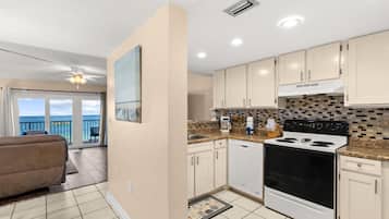 A modern kitchen with a large stove, white cabinets, and a view to the outside.