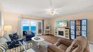 A living room with a sofa, armchair, and a coffee table. There is a fireplace and a painting on the wall.