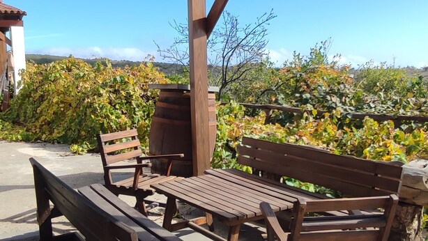 Eine hölzerne Bank und ein Tisch unter einer Pergola mit freiem Blick auf die umliegende Landschaft.