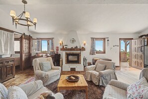 Un salon chaleureux avec une cheminée, des meubles en bois et une vue sur l’extérieur.